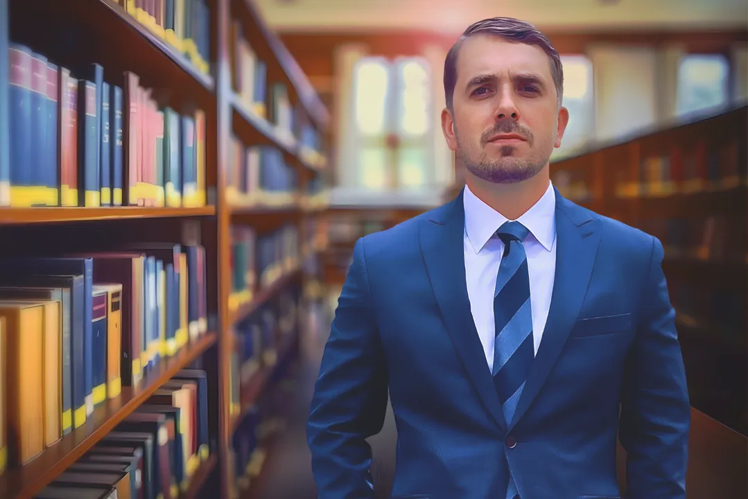 Attorney in a blue suit standing in a law library, representing the personal injury team at Burdzy & Associates in New York.